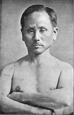 Das Foto zeigt Funakoshi Gichin. Wikimedia Commons bezeichnet die abgebildete Person als 船越義珍 (Funakoshi Gichin) und nennt als Herkunft das Buch 錬胆護身唐手術 (Rentan Goshin Karate Jutsu).