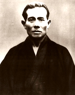 Wikimedia Commons bezeichnet die abgebildete Person als Uechi Kanbun (上地 完文). Die bereitgestellte Datei stimmt bytegleich mit dem Commons-Original überein. URK ist der Uploader; die Dateibeschreibung weist keinen gesicherten Fotografen und keine Originalquelle aus.